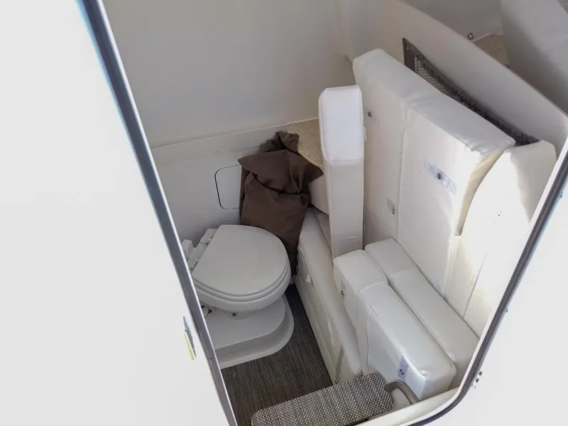Slide: The Image of 2024 Regulator 28 boat interior with compact toilet and cushioned seating. - 15