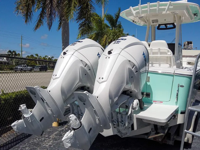 Slide: The Image of 2024 Regulator 28 boat with twin outboard engines, docked near palm trees. - 28