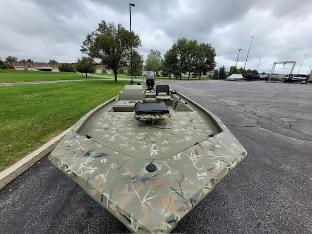 Slide: The Image of 2024 Tracker Grizzly 1754 SC camo boat parked on asphalt near green grass and trees. - 4