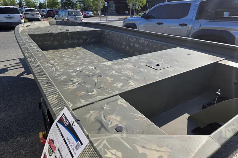 Slide: The Image of 2024 Tracker Grizzly 1754 Jon boat with camouflage design, parked outdoors. - 3