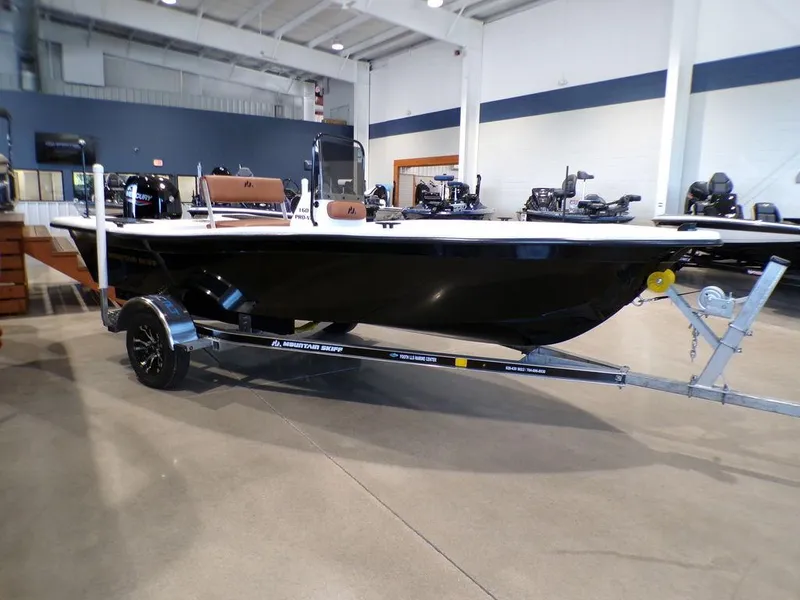 Slide: The Image of 2024 Skiff 160 PRO-Vee boat on trailer in showroom, featuring sleek black design. - 3