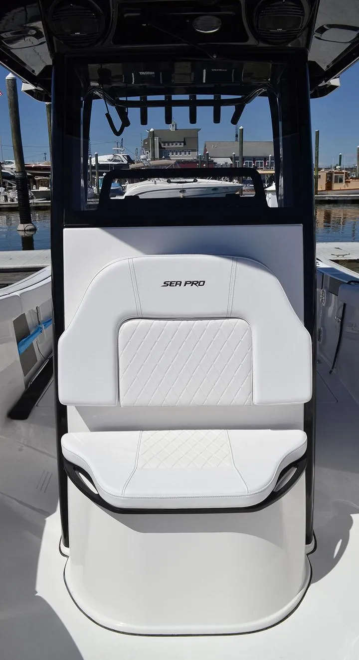 Slide: The Image of 2024 Sea Pro 262 DXL boat interior with white seating at a marina. - 6