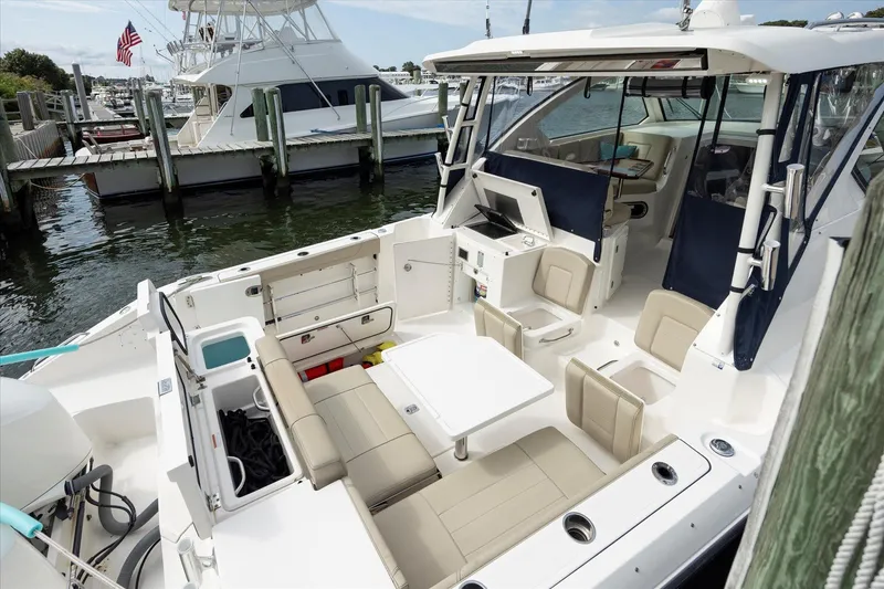 Slide: The Image of 2016 Pursuit OS 355 Offshore boat interior with seating and table at dock. - 14
