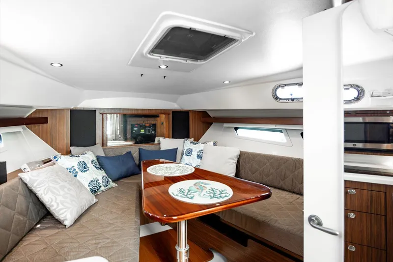 Slide: The Image of 2016 Pursuit OS 355 Offshore cabin interior with cozy seating and elegant wooden table. - 18