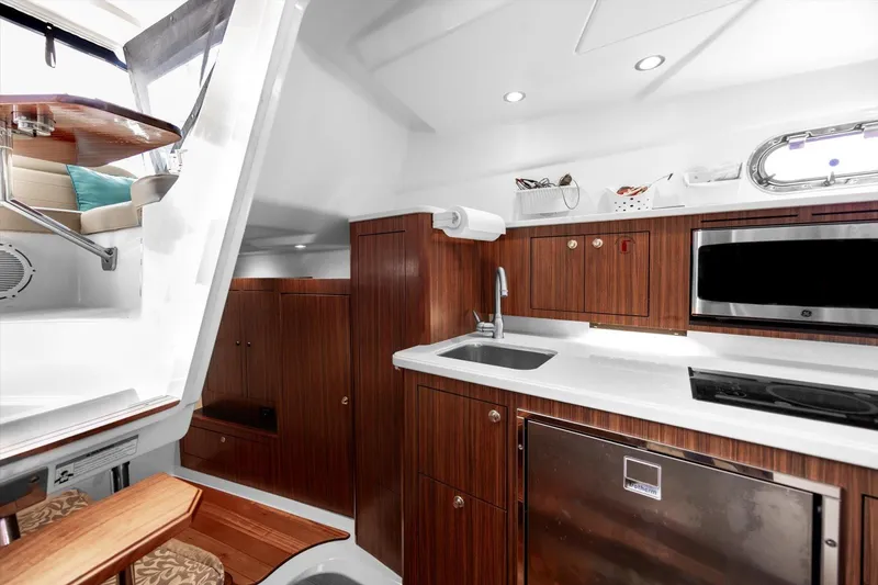 Slide: The Image of 2016 Pursuit OS 355 Offshore yacht interior with modern kitchen and wooden cabinetry. - 19