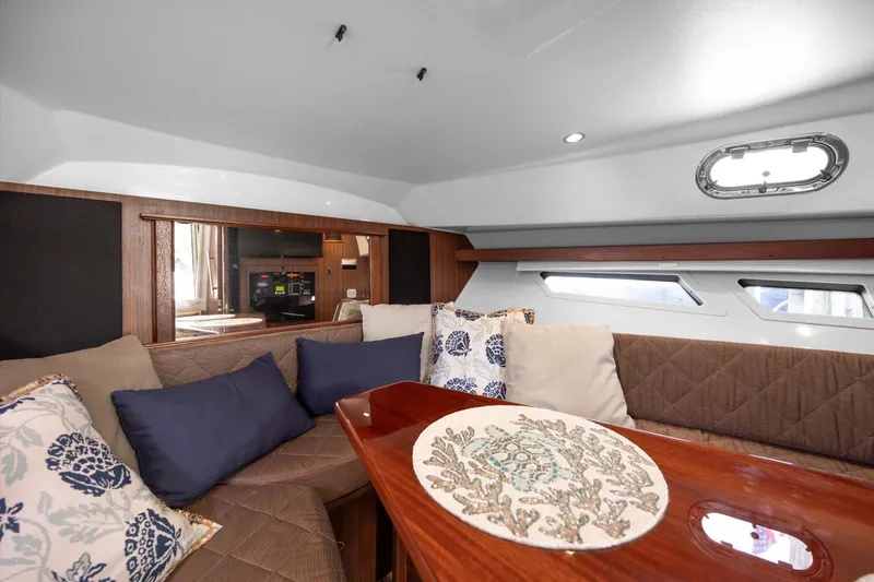 Slide: The Image of 2016 Pursuit OS 355 Offshore cabin with cozy seating and decorative pillows. - 24