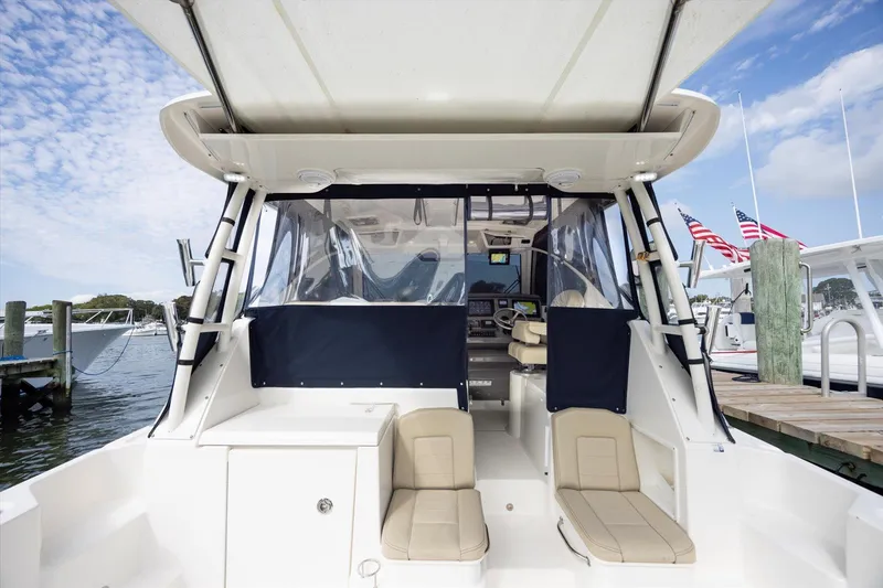 Slide: The Image of 2016 Pursuit OS 355 Offshore boat docked, featuring spacious seating and clear skies. - 26