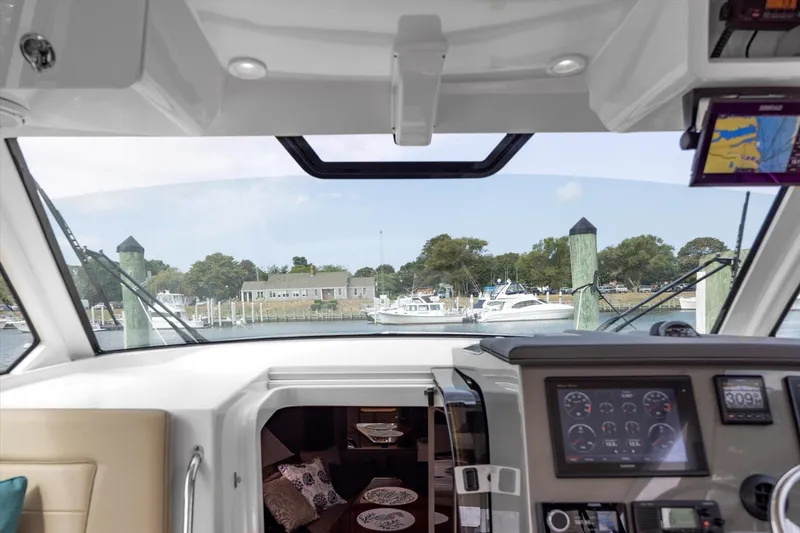 Slide: The Image of Interior view of 2016 Pursuit OS 355 Offshore boat cockpit with marina in background. - 29