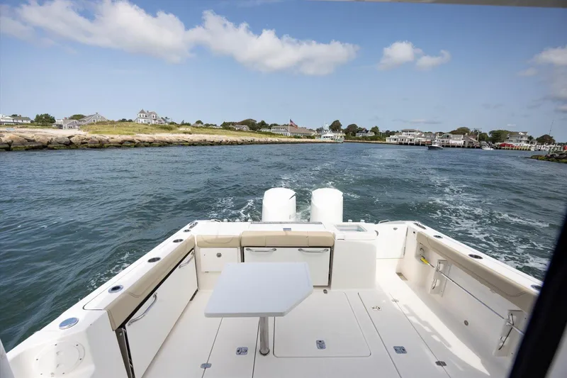 Slide: The Image of 2016 Pursuit OS 355 Offshore boat cruising near a coastal town under a blue sky. - 34