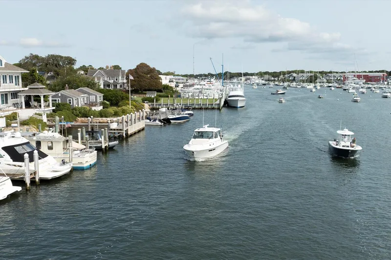 Slide: The Image of 2016 Pursuit OS 355 Offshore cruising in a scenic marina with boats and waterfront homes. - 7