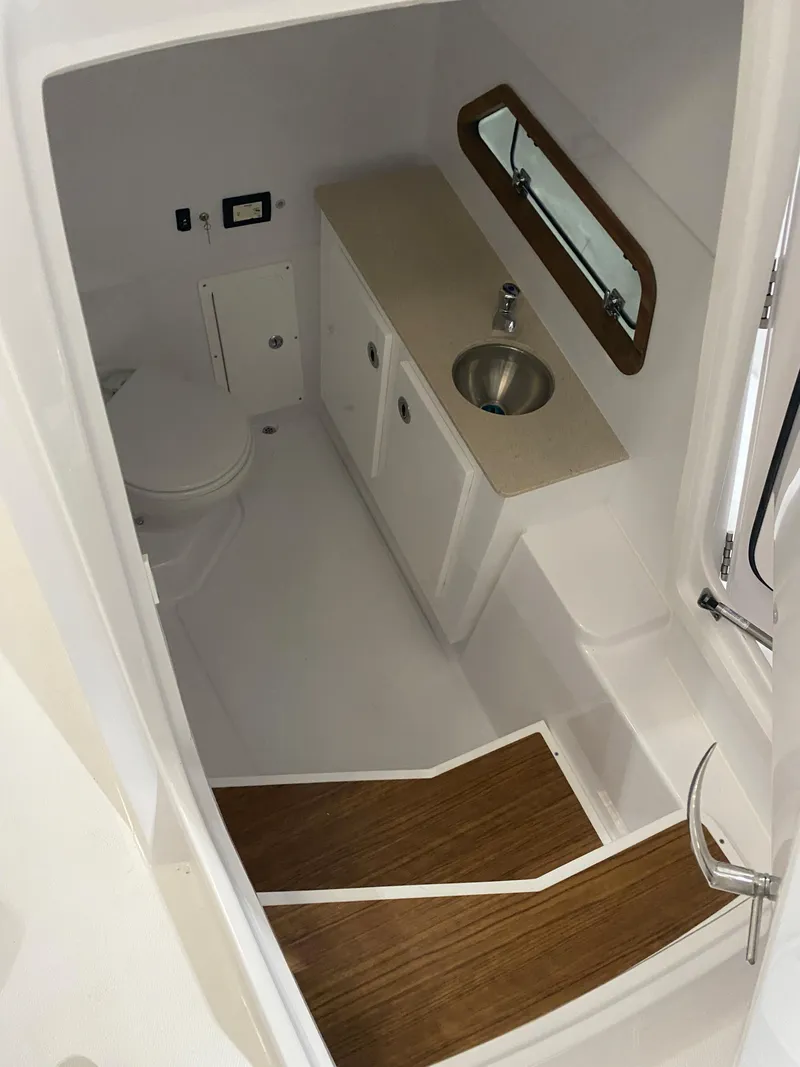 Slide: The Image of Interior of 2023 Bertram 28 CC boat featuring a compact bathroom with sink and toilet. - 9