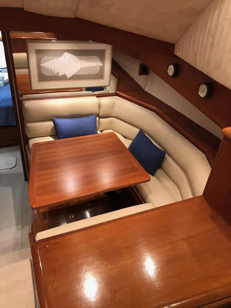 Slide: The Image of 1990 Viking 38 Convertible yacht interior with wooden table, cushioned seating, and nautical decor. - 12