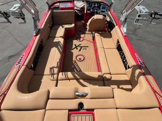 Slide: The Image of 2019 MasterCraft XT25 boat interior with tan seating and red accents. - 12