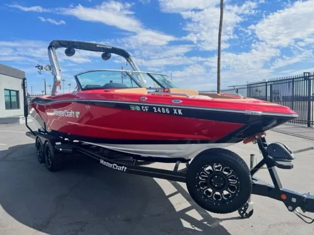 Slide: The Image of 2019 MasterCraft XT25 red boat on trailer under blue sky. - 4