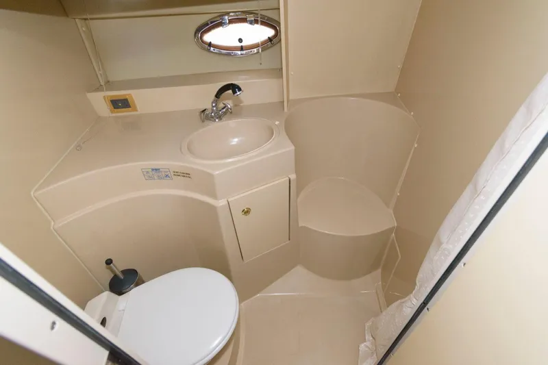Slide: The Image of 2002 Cruisers Yachts 3372 Express bathroom with sink, toilet, and porthole window. - 22