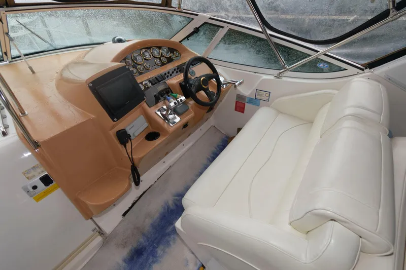 Slide: The Image of 2002 Cruisers Yachts 3372 Express helm with beige dashboard and white seating. - 9