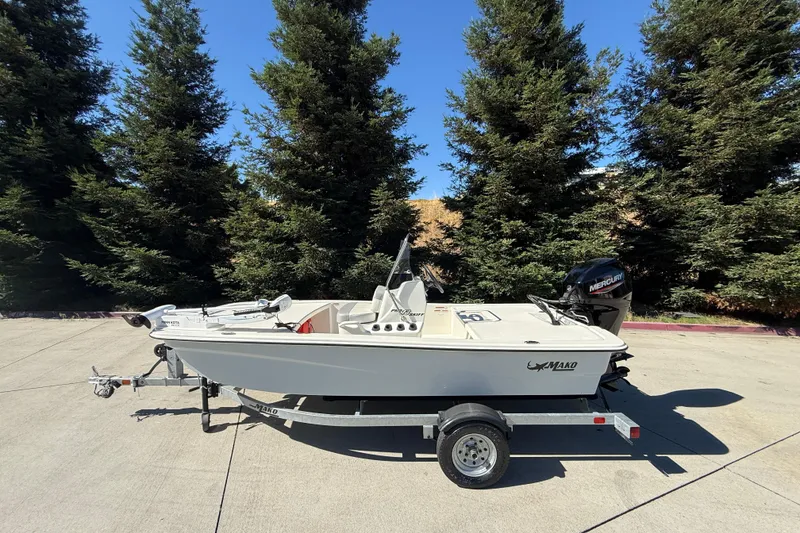 The Image of 2024 Mako Pro Skiff 13 CC boat on trailer, surrounded by trees. - 0