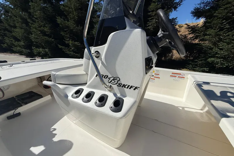 Slide: The Image of 2024 Mako Pro Skiff 13 CC boat interior with steering console and rod holders. - 6