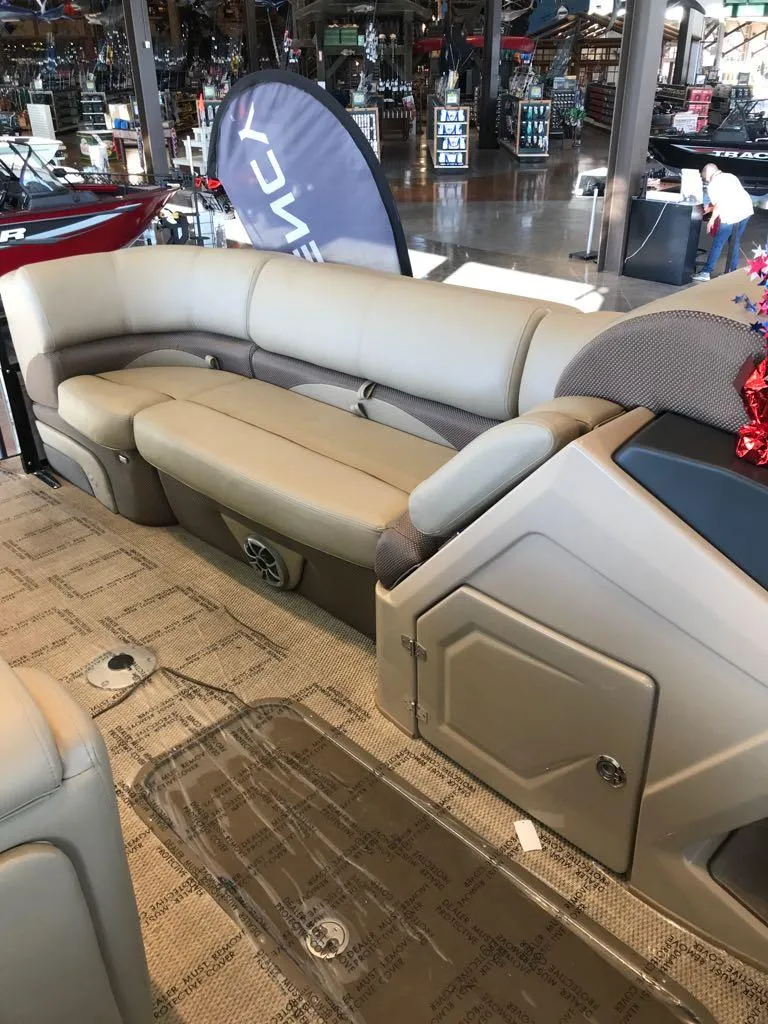 Slide: The Image of 2024 Regency 230 DL3 pontoon boat interior with beige seating and storage compartments. - 11