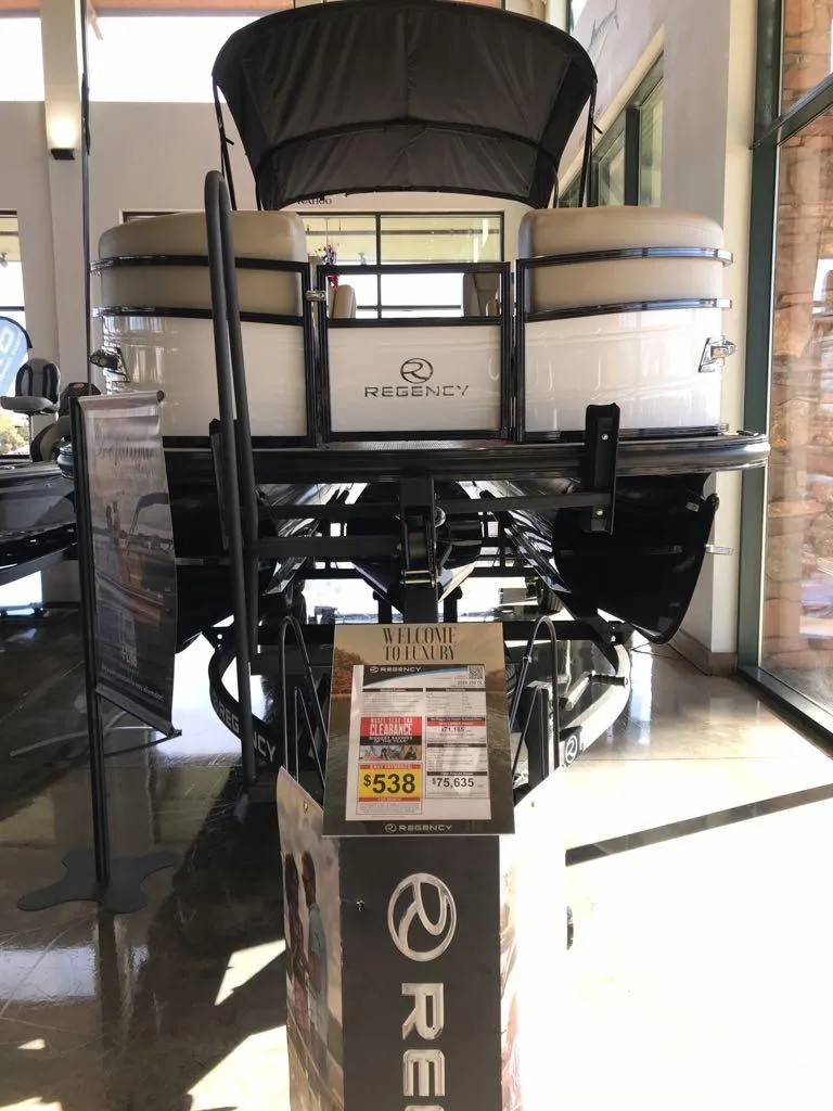 Slide: The Image of 2024 Regency 230 DL3 pontoon boat displayed indoors with price tag. - 3