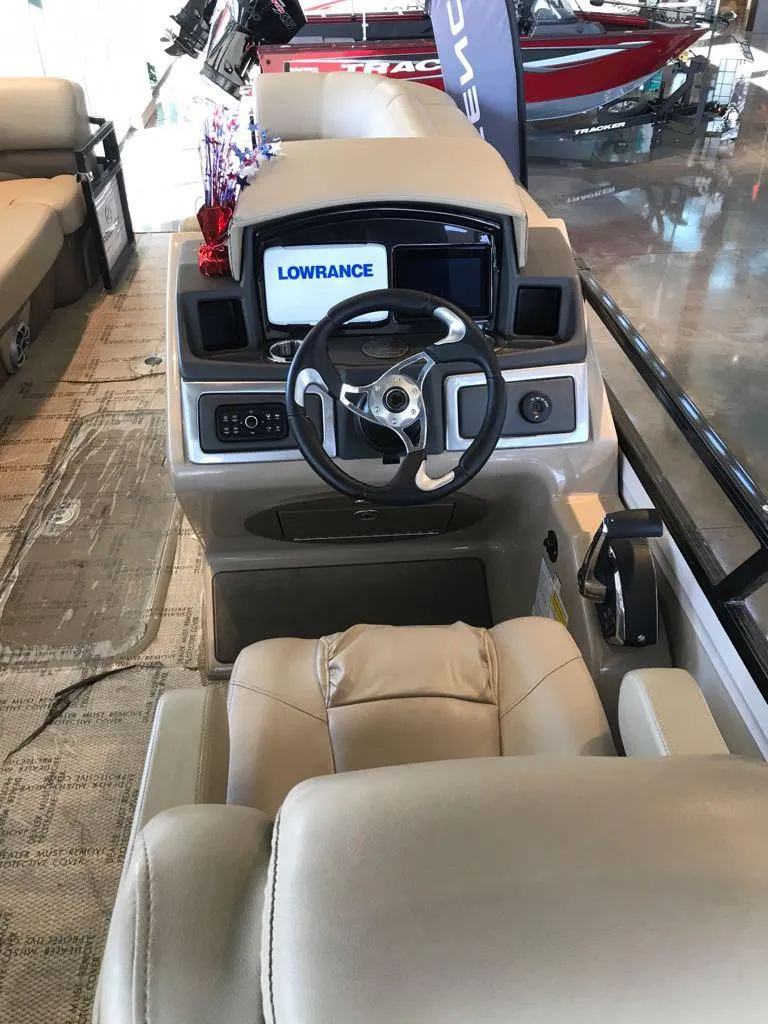 Slide: The Image of 2024 Regency 230 DL3 boat interior with Lowrance navigation system and beige seating. - 8