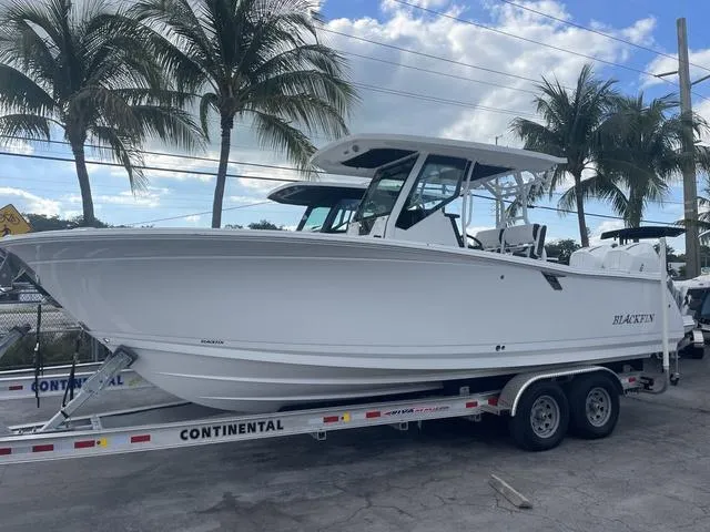 Slide: The Image of 2023 Blackfin 272CC boat on a Continental trailer with palm trees in the background. - 1