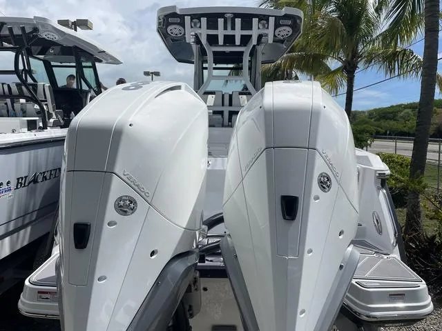 Slide: The Image of 2023 Blackfin 272CC boat with twin outboard engines, docked near palm trees. - 2