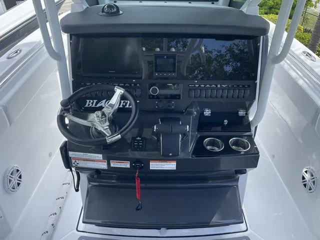 Slide: The Image of 2023 Blackfin 272CC boat console with steering wheel, controls, and cup holders. - 8