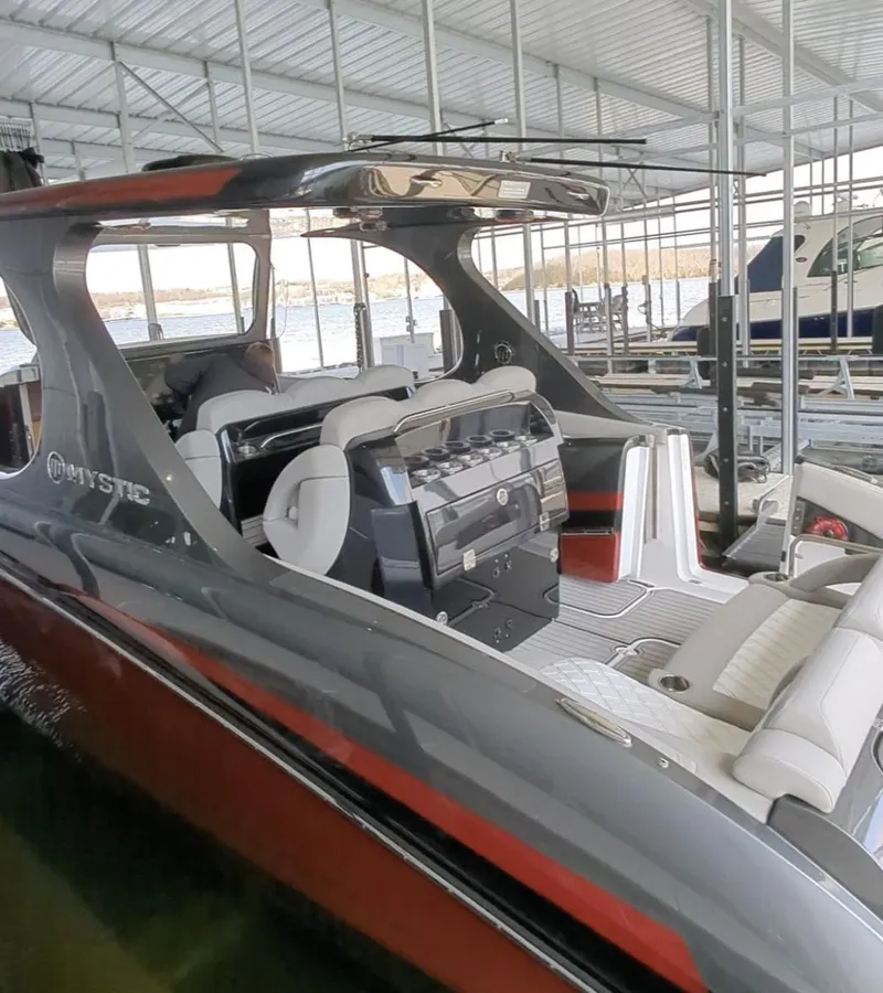 Slide: The Image of 2020 Mystic Powerboats M4200 in dock, sleek design, luxury seating, covered marina setting. - 2