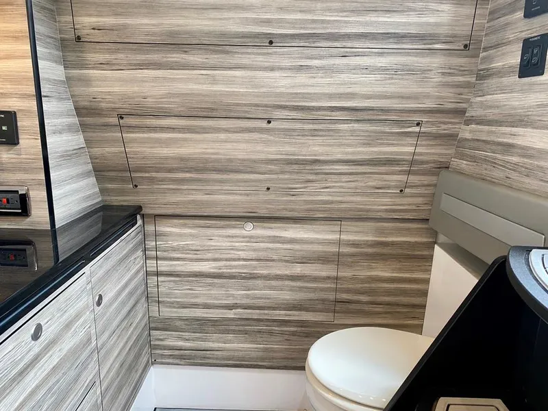 Slide: The Image of Interior of 2020 Mystic Powerboats M4200, featuring modern wood paneling and a compact toilet. - 36