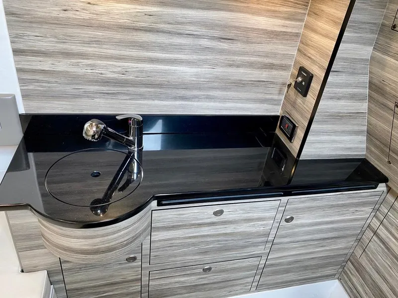 Slide: The Image of Modern bathroom vanity in 2020 Mystic Powerboats M4200, featuring sleek black countertop and wood paneling. - 37