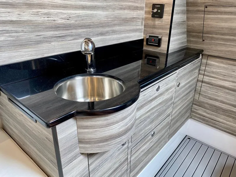 Slide: The Image of Modern sink area in 2020 Mystic Powerboats M4200 with sleek wood finish and black countertop. - 38