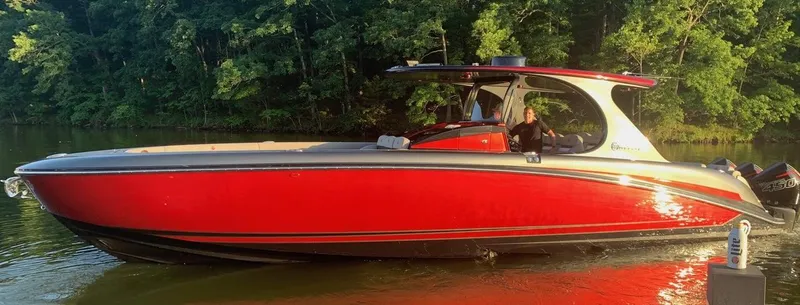 Slide: The Image of 2020 Mystic Powerboats M4200, red hull, cruising on a calm lake with lush greenery. - 4