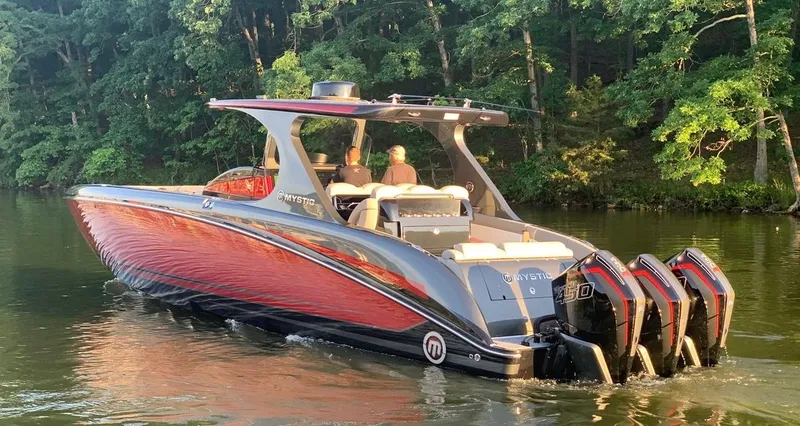 Slide: The Image of 2020 Mystic Powerboats M4200 cruising on a serene lake with lush green trees. - 5