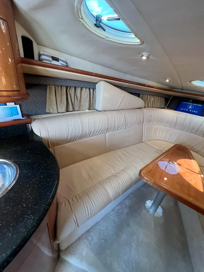 Slide: The Image of Interior of a 2003 Cobalt 360 boat with beige seating and wooden table. - 28