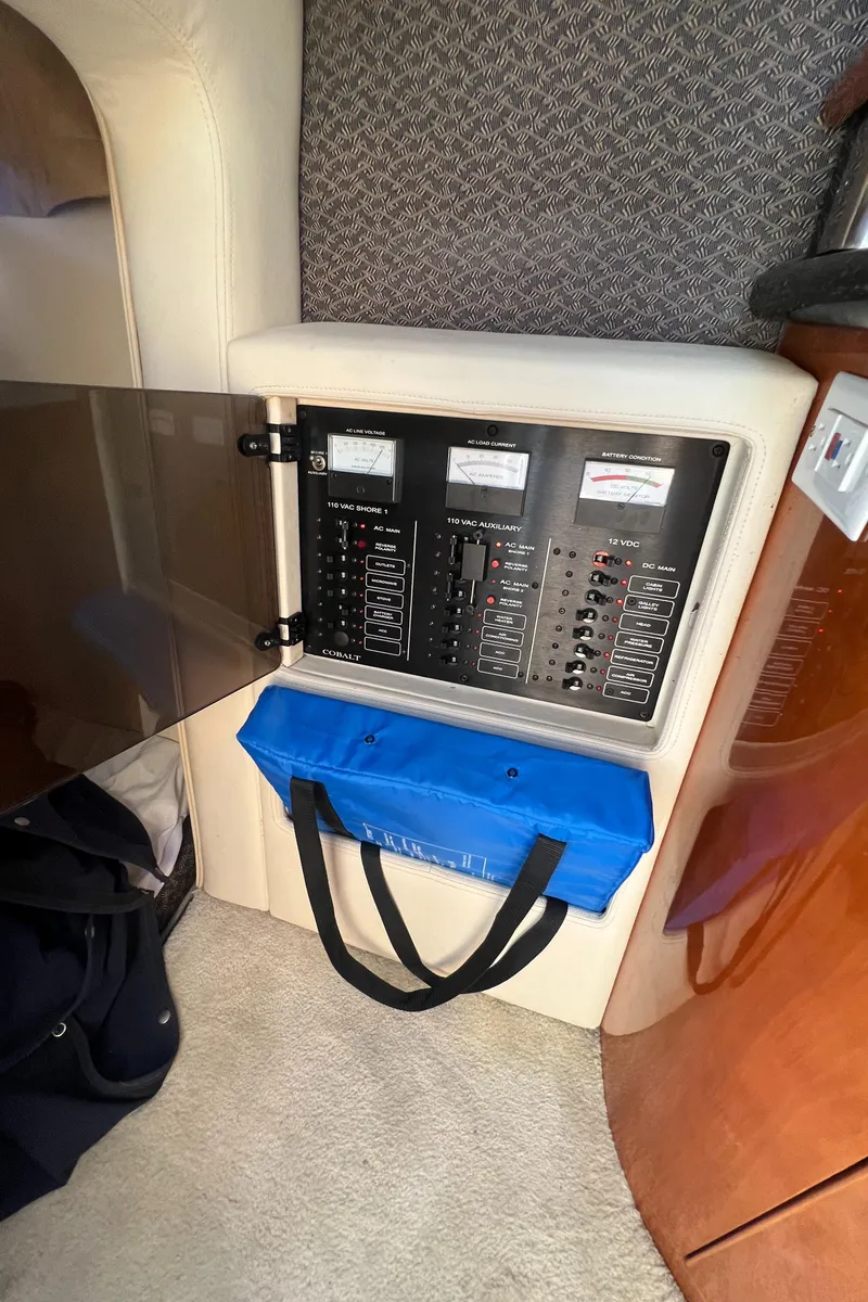 Slide: The Image of Electrical panel inside a 2003 Cobalt 360 boat with a blue storage bag. - 34