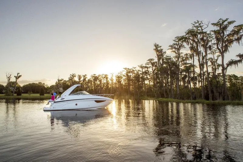 Slide: The Image of 2024 Regal 28 Express boat cruising on a serene lake at sunset. - 14