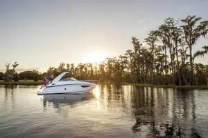 Slide: The Image of 2024 Regal 28 Express boat cruising on a serene lake at sunset. - 28