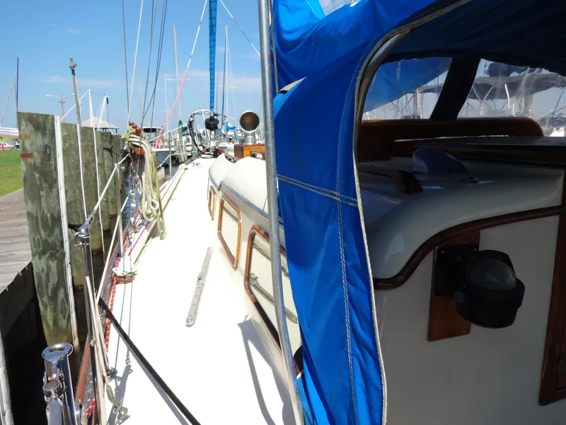 Slide: The Image of 1966 Cheoy Lee 36 Offshore Flying Buffalo sailboat docked, featuring blue canopy and wooden accents. - 10