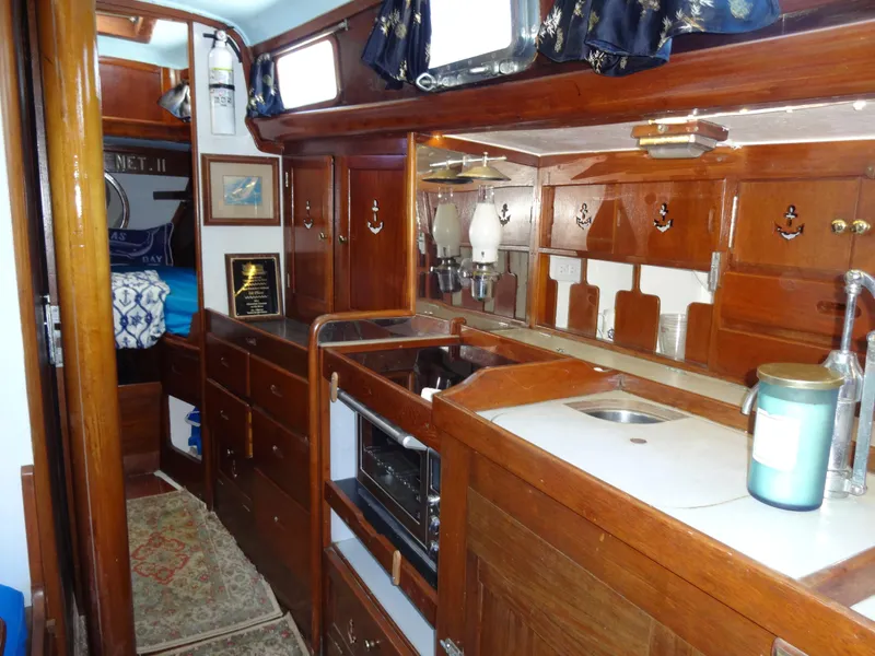 Slide: The Image of 1966 Cheoy Lee 36 Offshore Flying Buffalo interior with wooden cabinetry and compact kitchen area. - 29