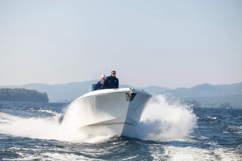 Slide: The Image of 2022 Comitti ISOLA 33 Sport SD cruising on a lake with mountains in the background. - 33