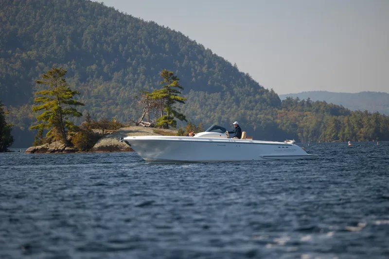 Slide: The Image of 2022 Comitti ISOLA 33 Sport SD boat cruising on a scenic lake with forested hills. - 38