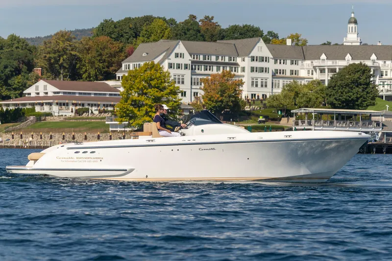 Slide: The Image of 2022 Comitti ISOLA 33 Sport SD boat cruising on a scenic lake near a large building. - 48