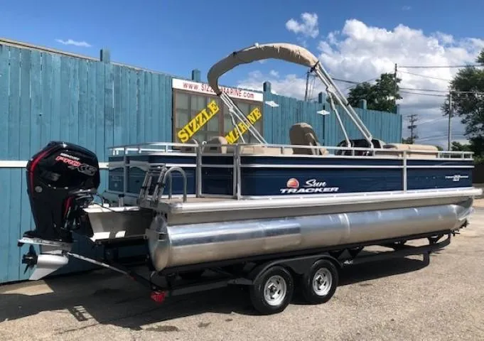 Slide: The Image of 2024 Sun Tracker Fishin' Barge 22 DLX pontoon boat with outboard motor on trailer. - 2