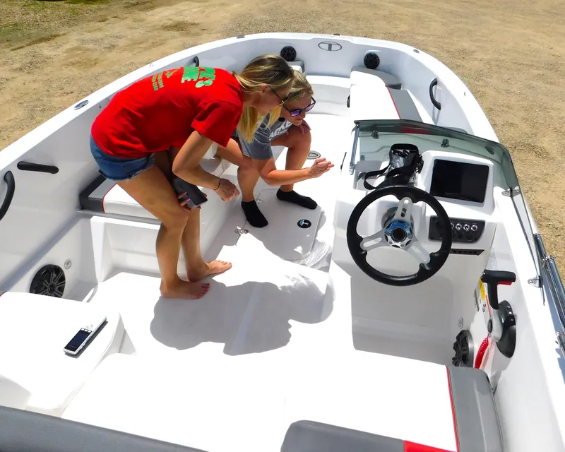 Slide: The Image of Two people inspecting a 2024 Tahoe T18 boat's interior on a sunny day. - 22