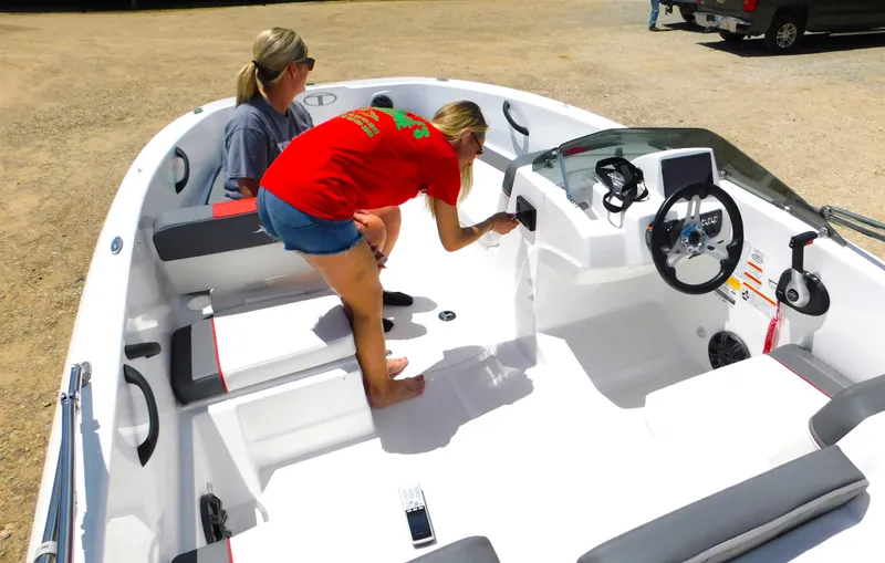 Slide: The Image of 2024 Tahoe T18 boat interior with two people, steering console, and seating. - 37
