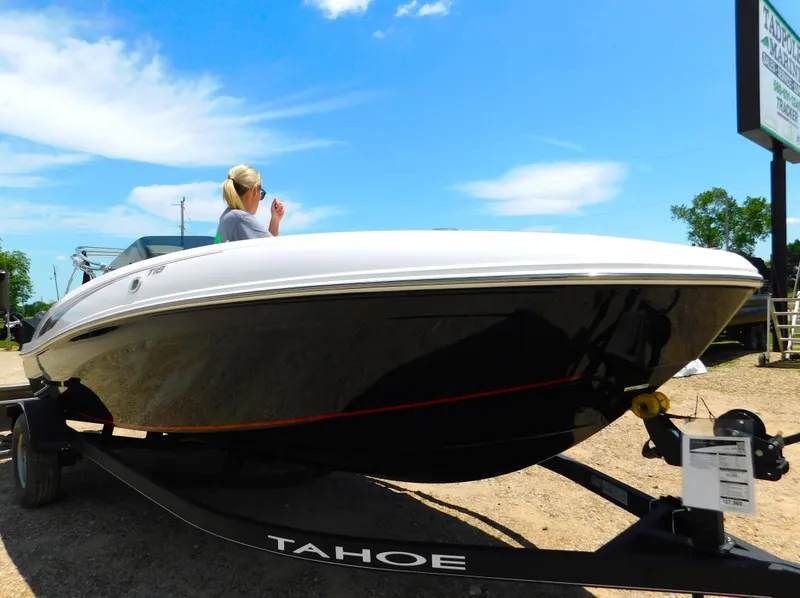 Slide: The Image of 2024 Tahoe T18 boat on trailer with person standing, clear sky background. - 5