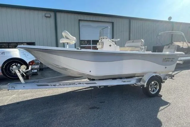 Slide: The Image of 2024 Carolina Skiff 19LS boat on trailer, parked outside a warehouse. - 10