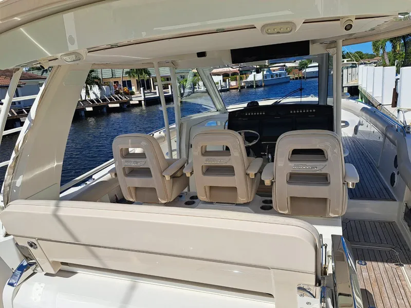 Slide: The Image of 2016 Boston Whaler 420 Outrage boat interior with helm seats and waterfront view. - 15