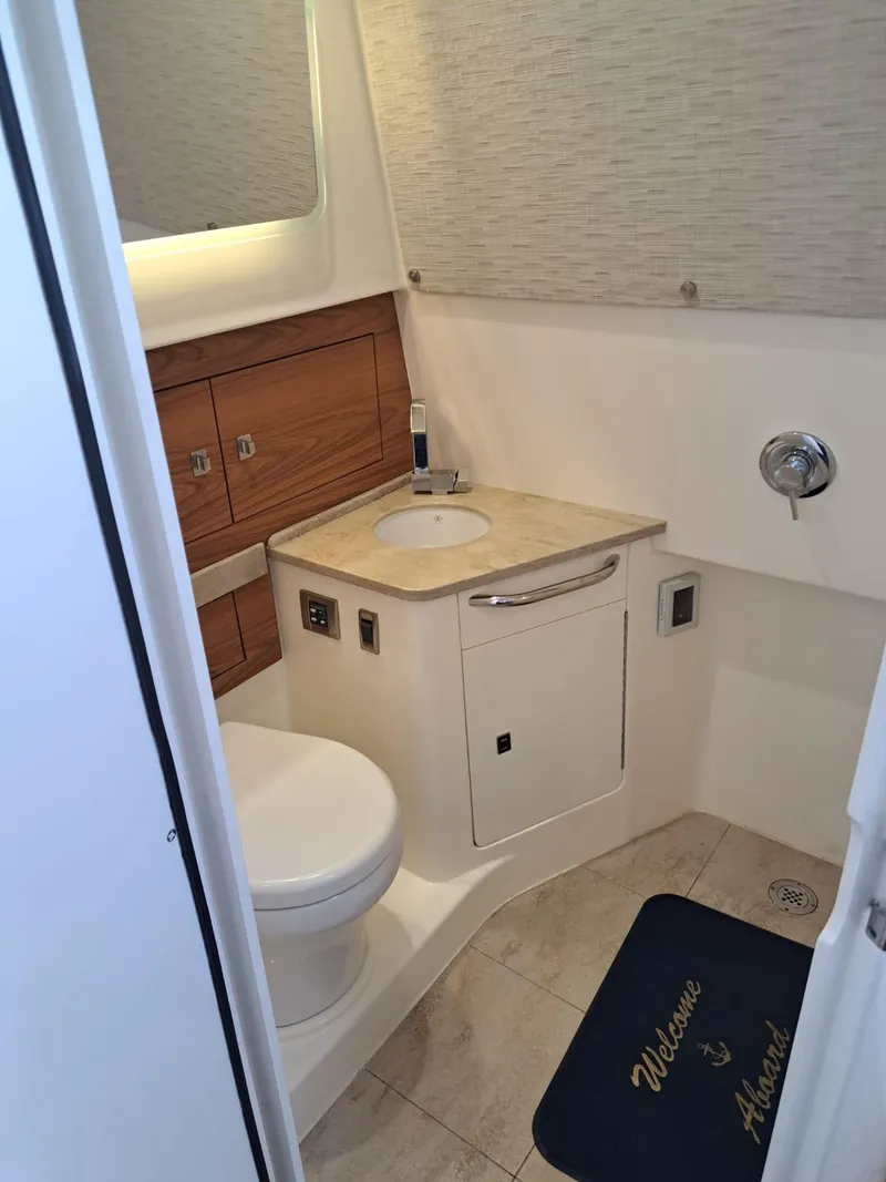 Slide: The Image of 2016 Boston Whaler 420 Outrage bathroom with sink, toilet, and storage cabinets. - 33
